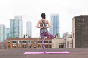 woman standing on pink yoga mat meditating